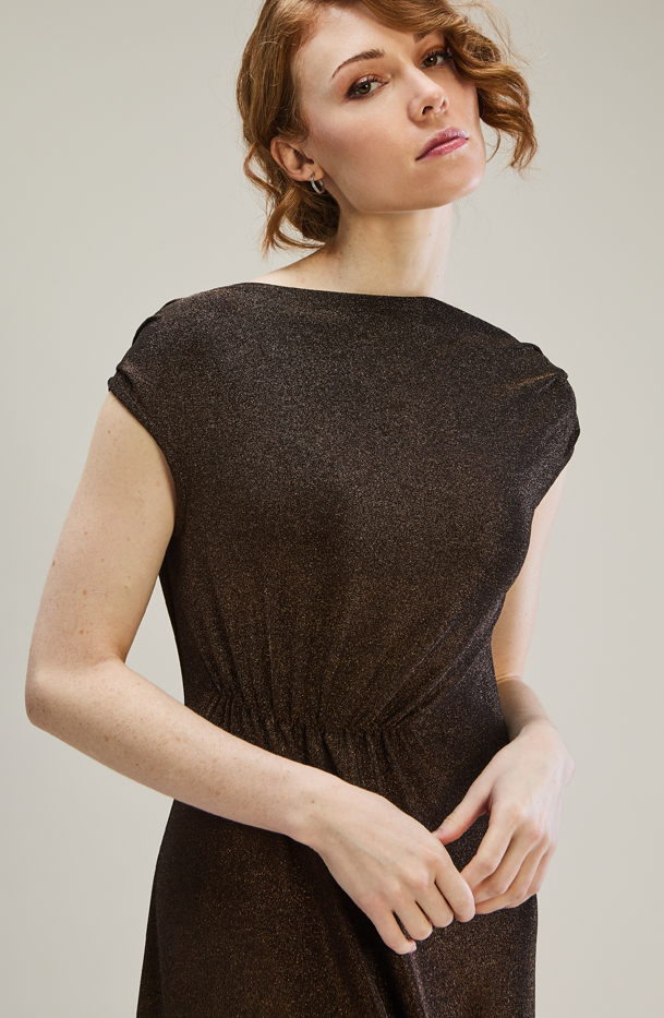 Woman wearing a brown dress against a plain background